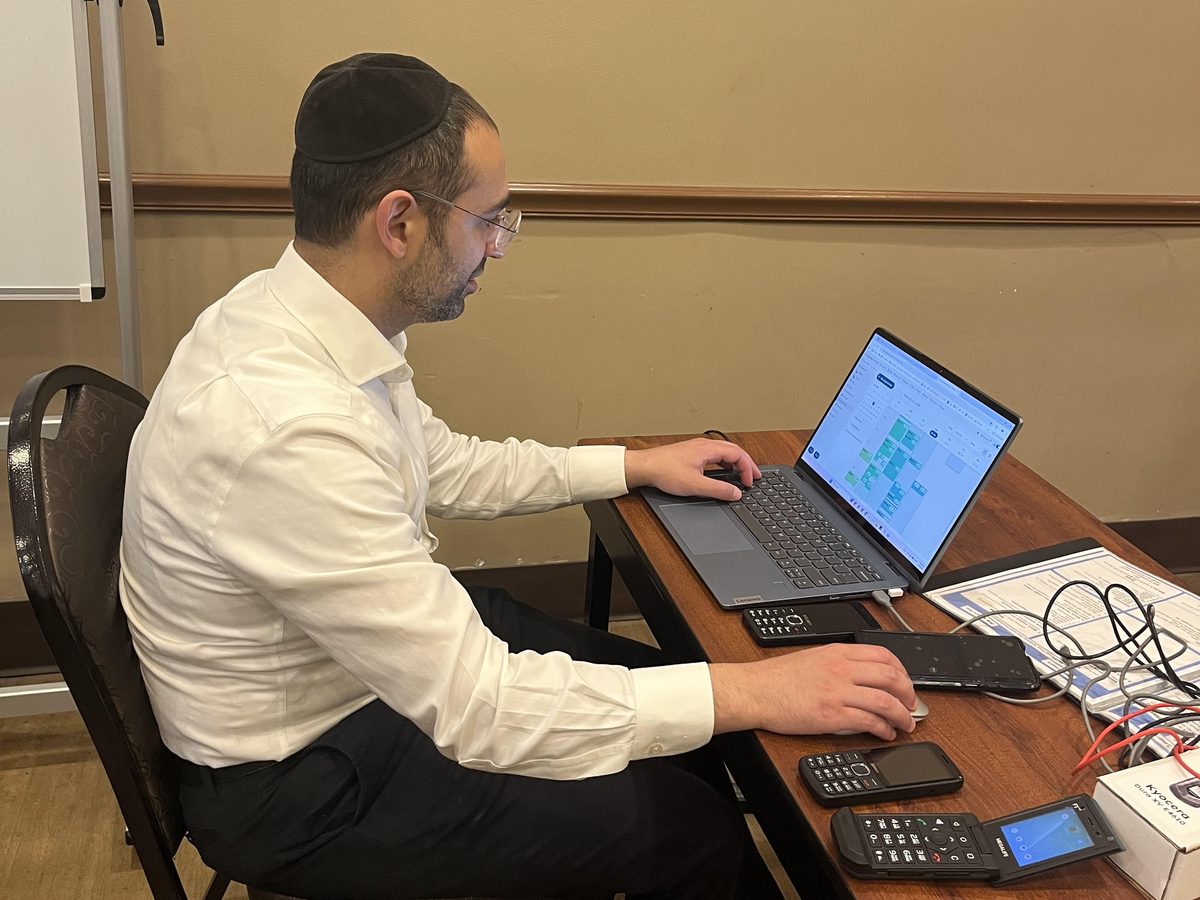 A Smart Connections NY team member setting up filtering on a tablet, with a laptop and devices on the desk